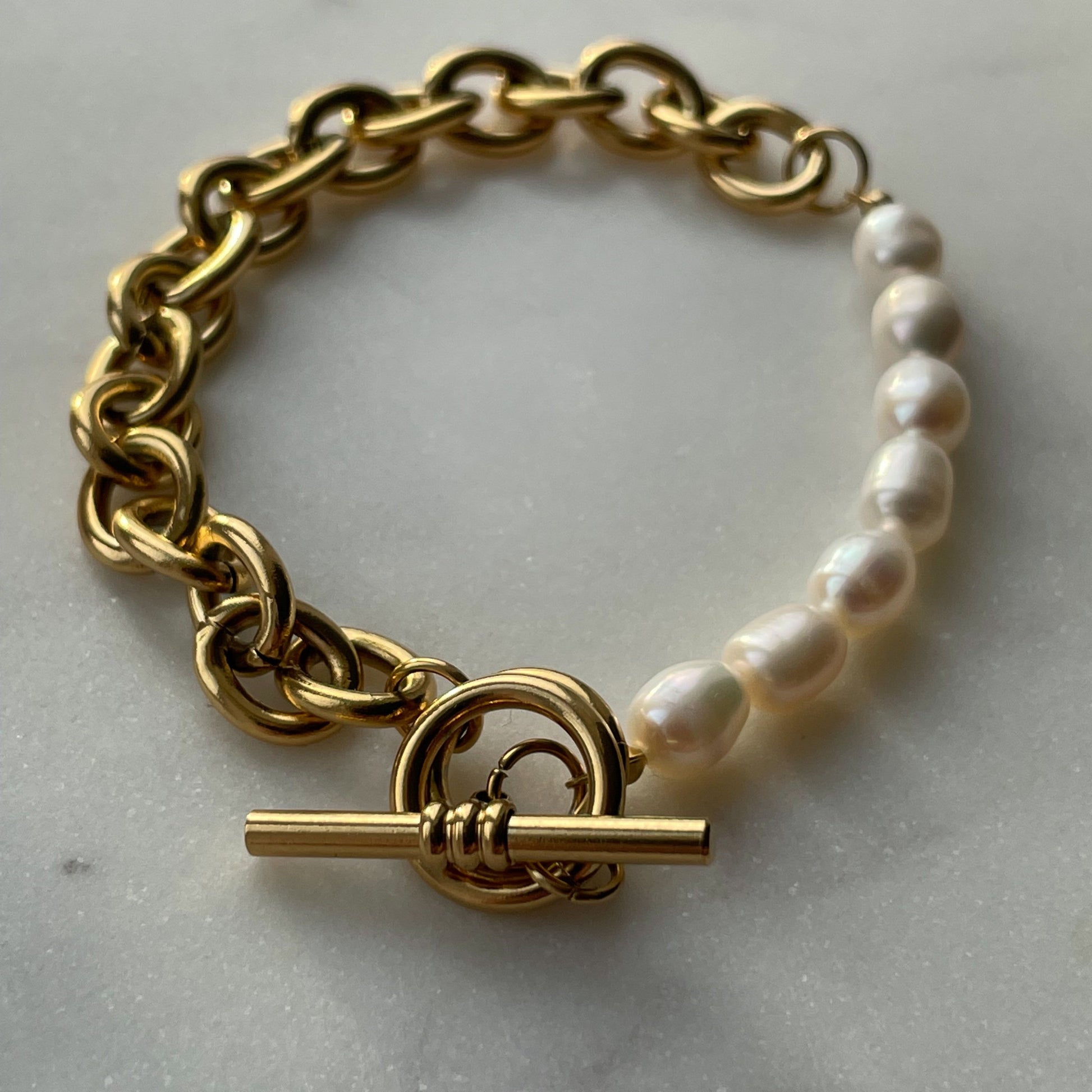 Elegant gold-plated link chain bracelet with perfectly round freshwater pearls. Features a toggle clasp, durable stainless steel, and a timeless design for everyday luxury.