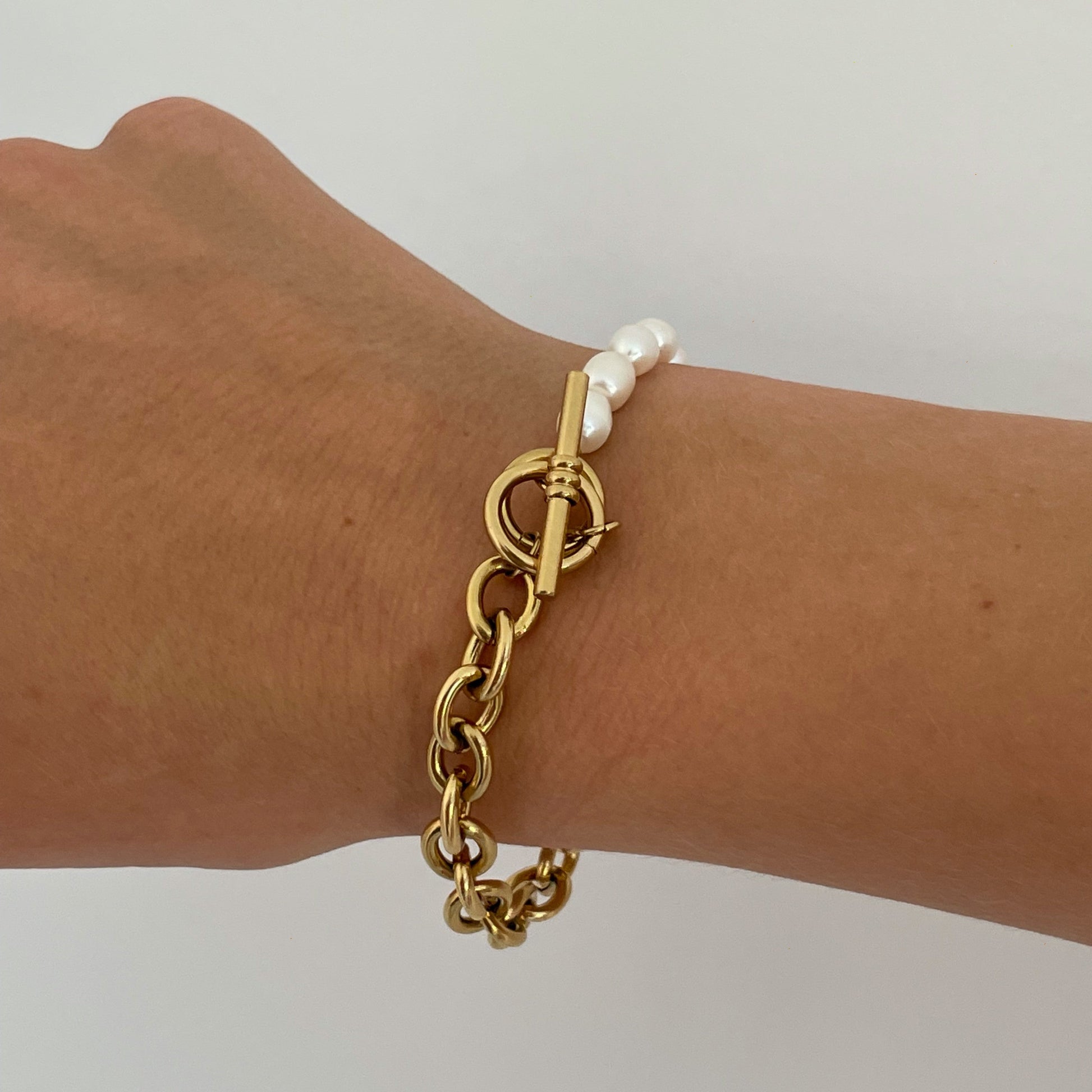 Elegant gold-plated link chain bracelet with perfectly round freshwater pearls. Features a toggle clasp, durable stainless steel, and a timeless design for everyday luxury.