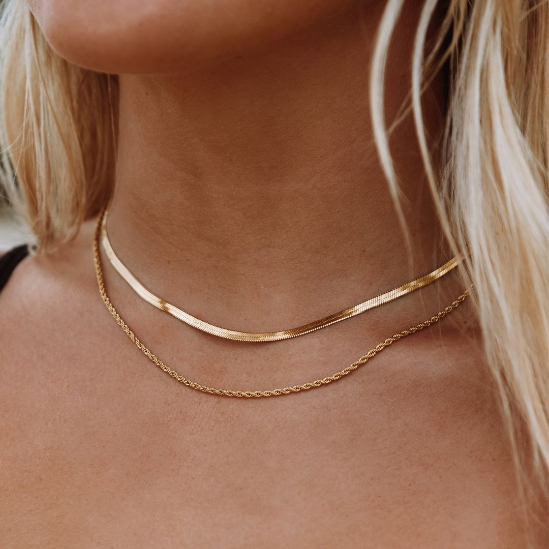 Elegant 18K gold-plated layered necklace with a herringbone choker and a delicate rope chain. Waterproof, sweatproof, and hypoallergenic for effortless elegance.