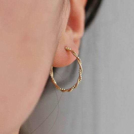 Elegant twisted hoop earrings in 14K solid gold. 20mm in diameter, lightweight, and perfect for everyday or special occasions.